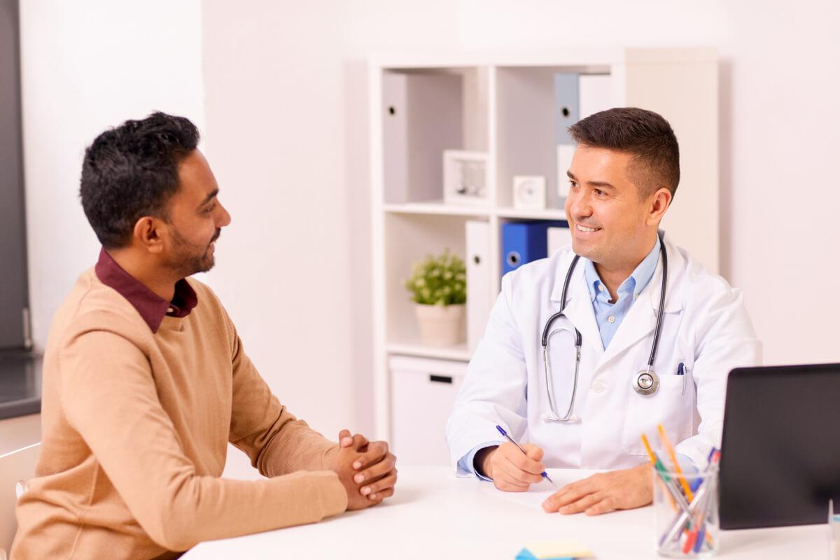 Doctor and patient smile and talk while exemplifying why patients stay rather than why patients leave their doctor
