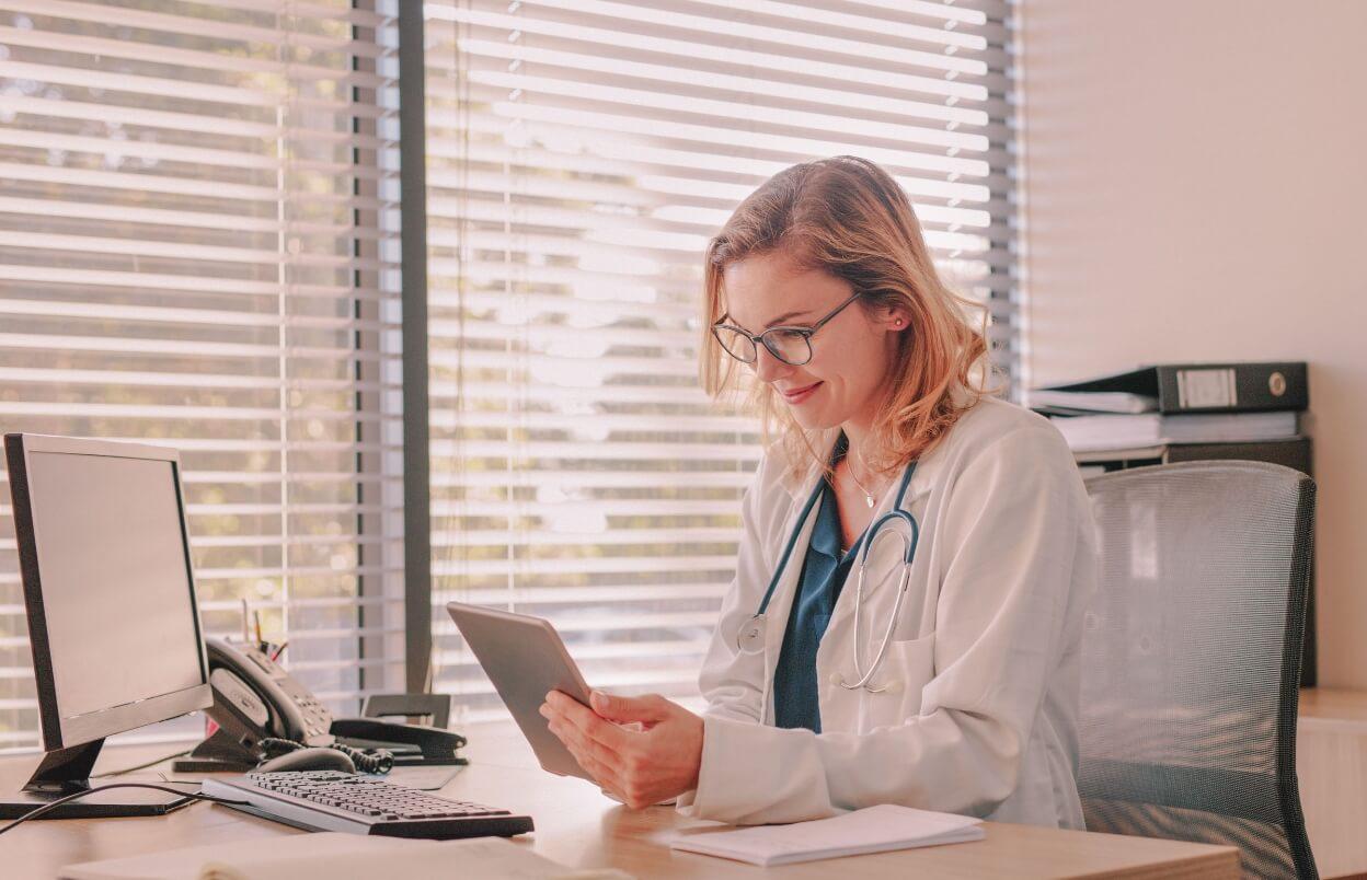 Doctor looking at tablet for practice website.