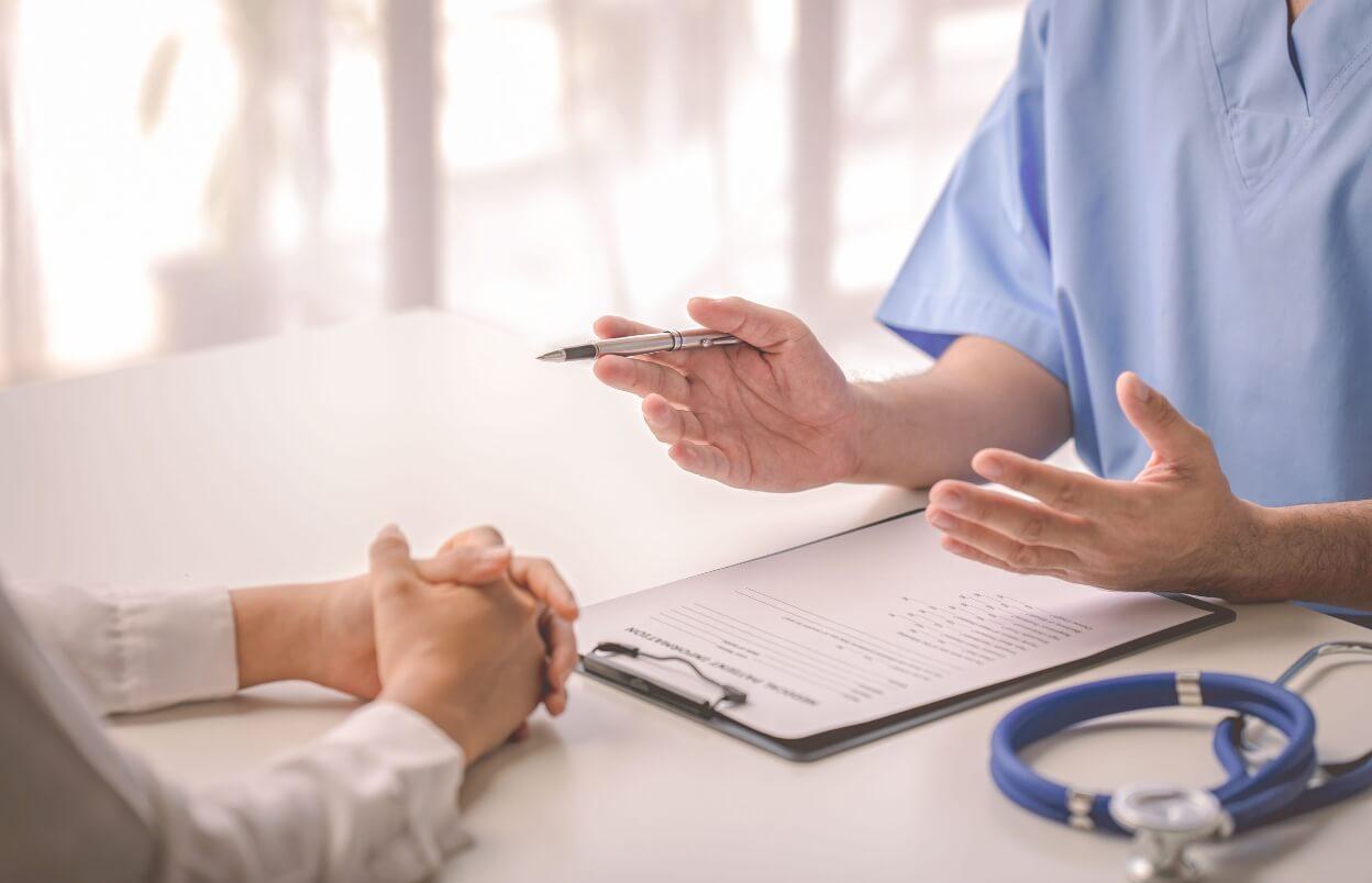 Doctor talking to patient and filling out patient history while keeping HIPAA compliance in mind.