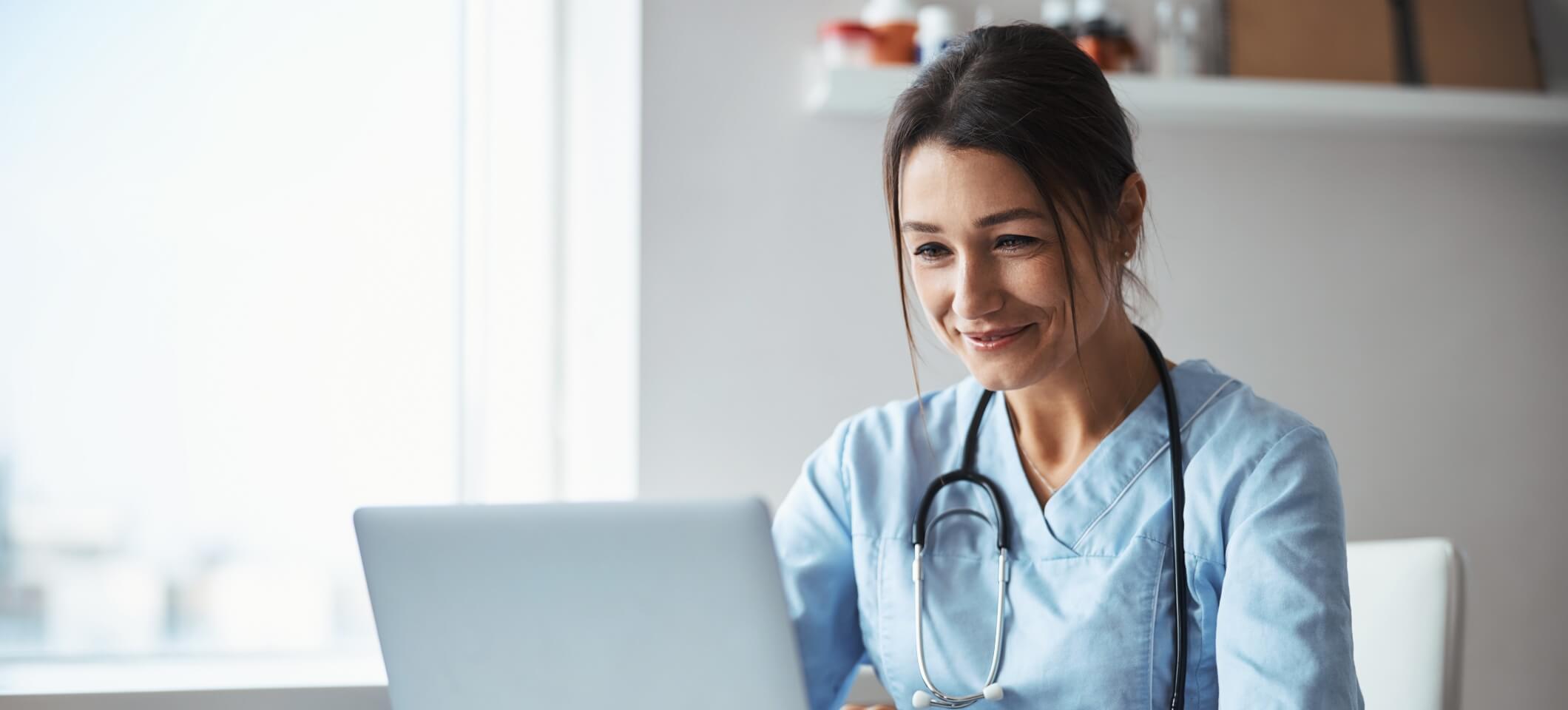 female doctor smiling and looking at computer