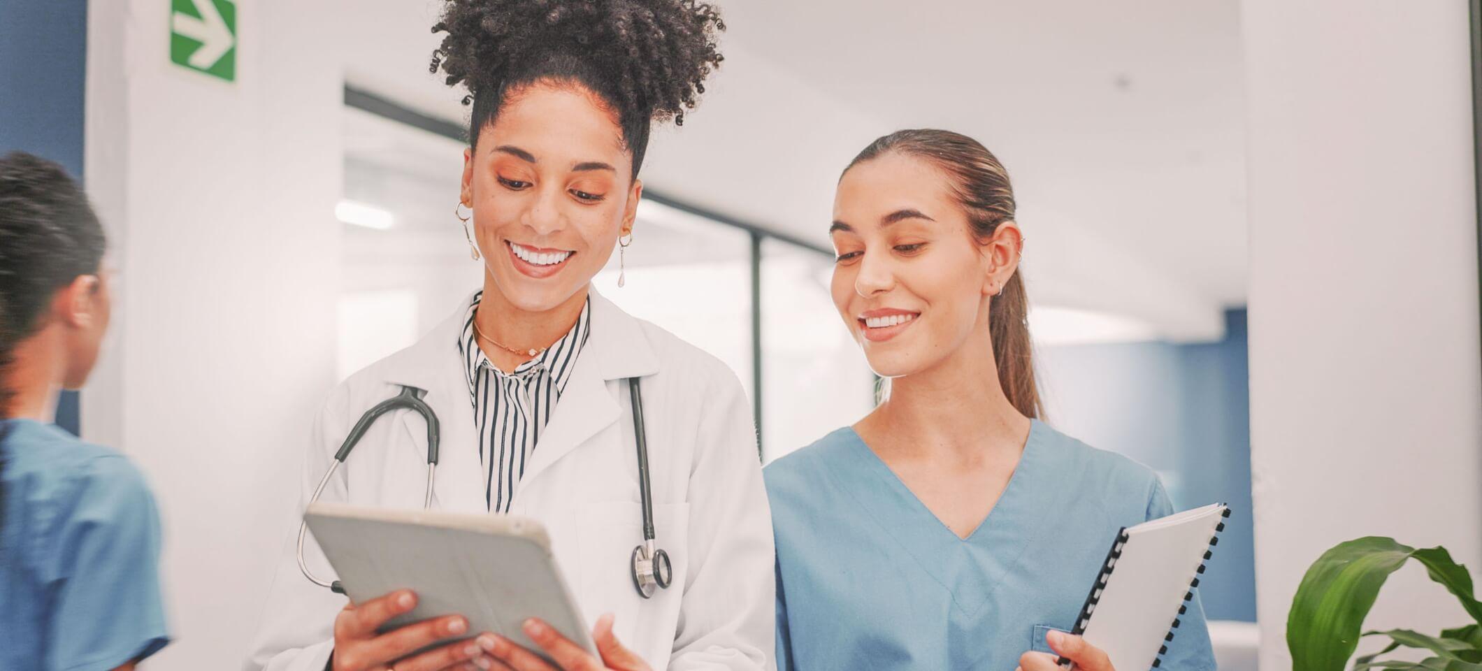 Female physician looking at digital tablet with medical practice staff member.
