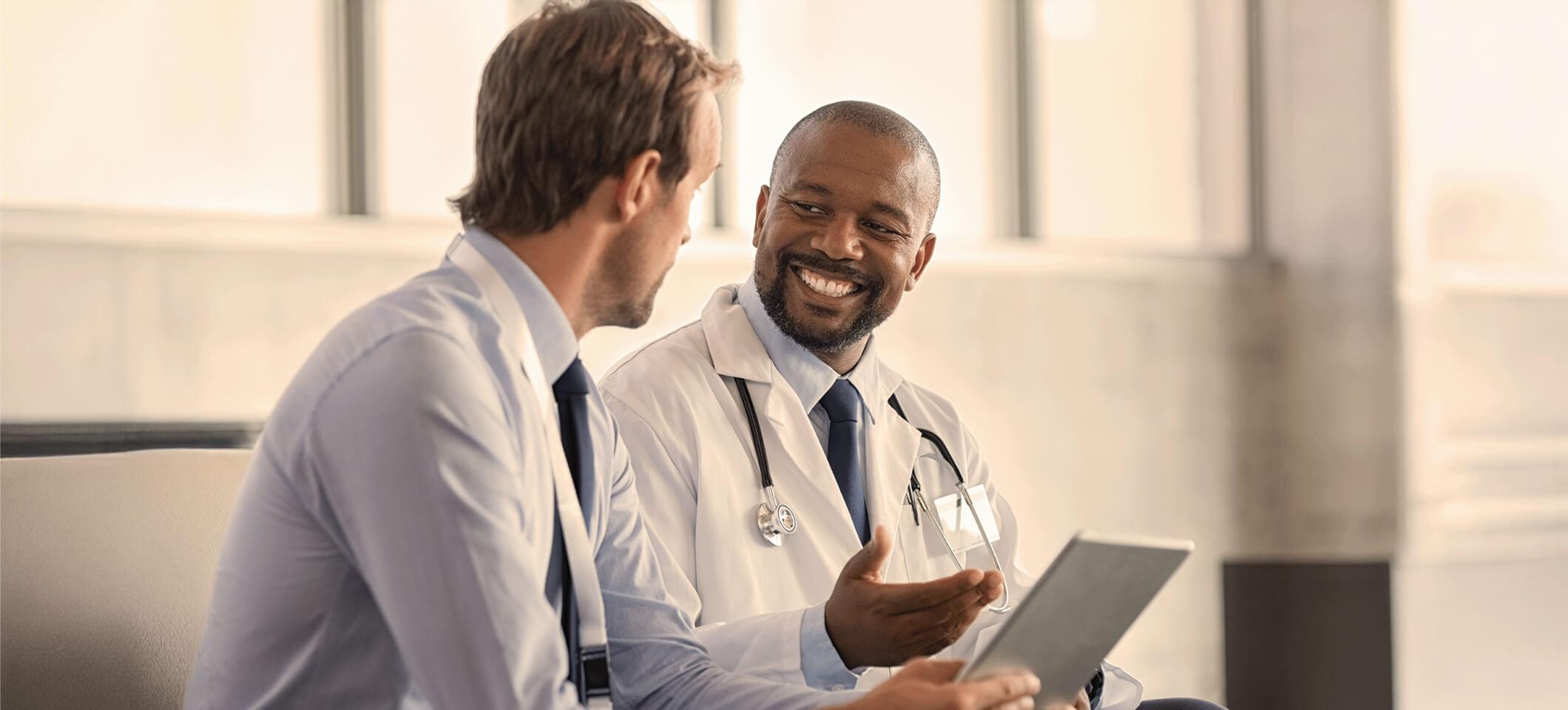 Physicians smile while holding computer and discussing EHR selection