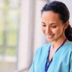 Smiling nurse works on tablet while experiencing the benefits of EHR for nurses