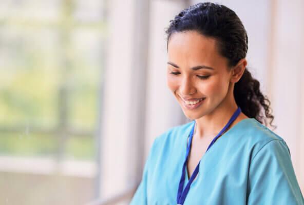 Smiling nurse works on tablet while experiencing the benefits of EHR for nurses