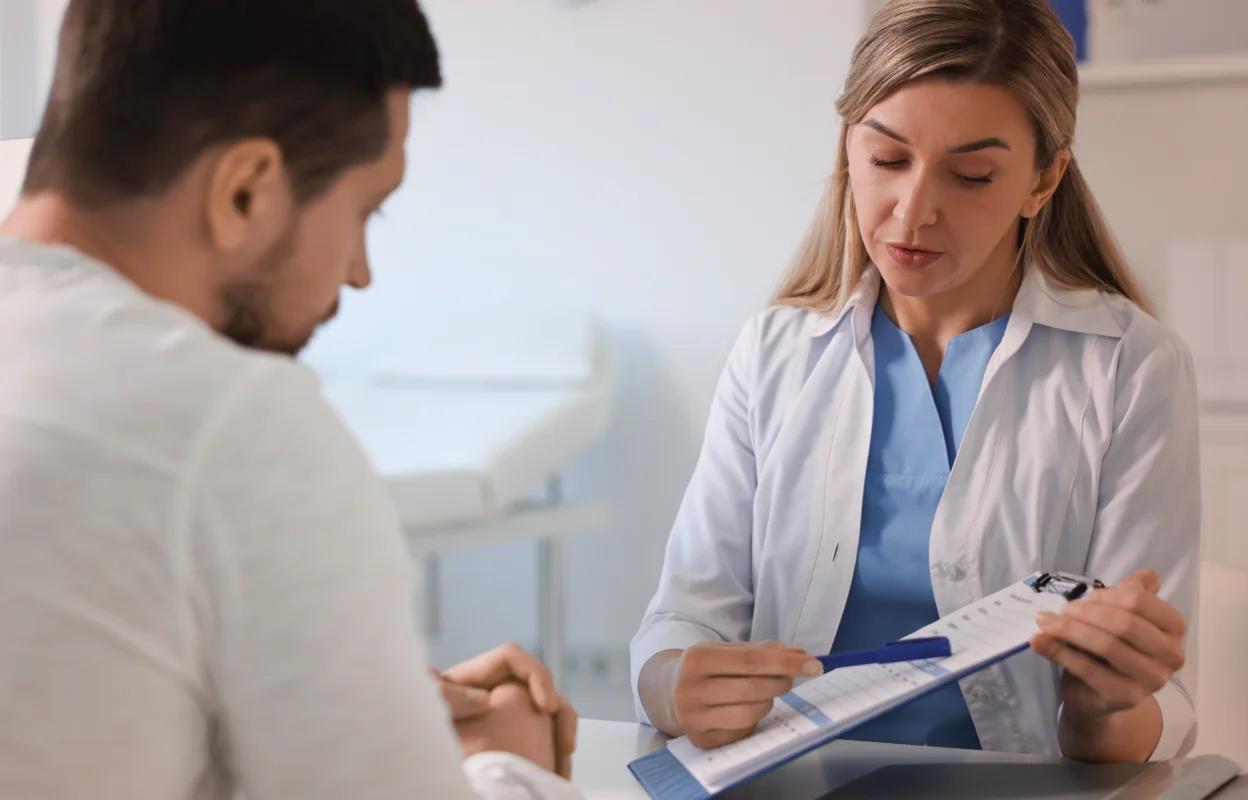 A healthcare professional discussing a chart with a patient in a clinical setting.