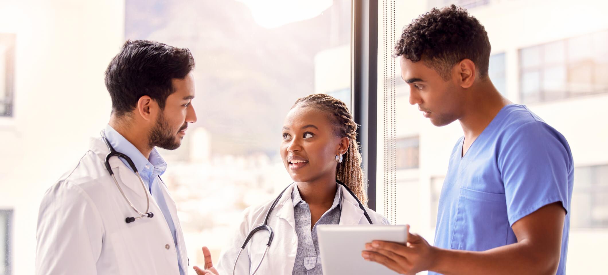 Physicians and clinical staff member look at tablet and collaborate on how to make prescribing easier