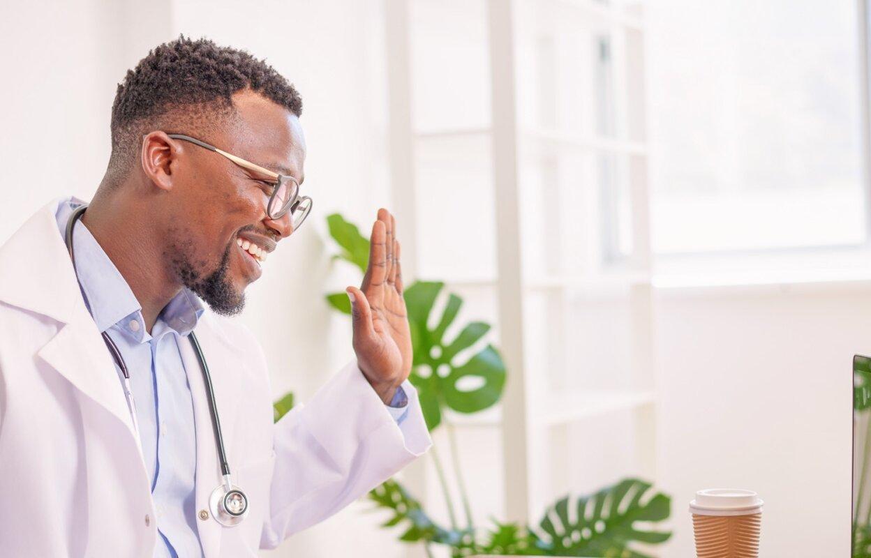 Smiling physician using telehealth software with patient