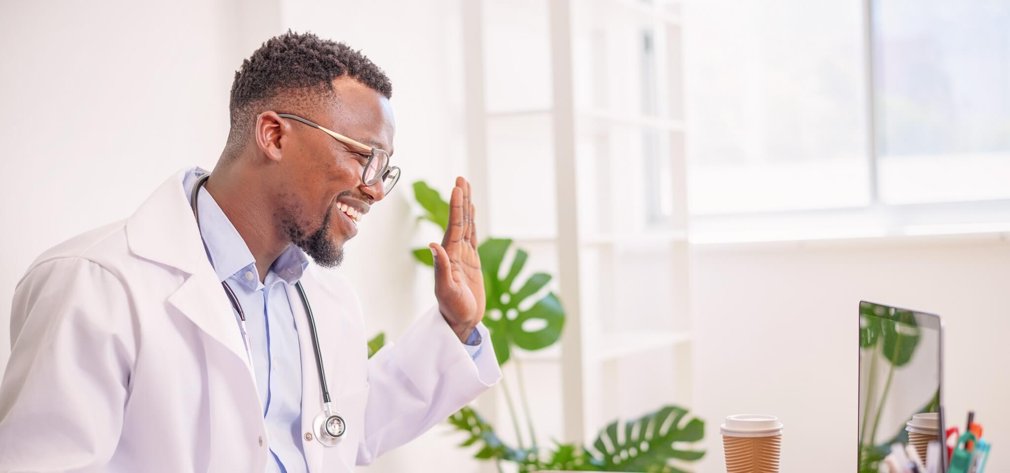 Smiling physician using telehealth software with patient