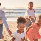 Family on beach observes UV Safety Month as part of July healthcare observances