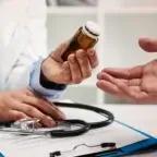 Healthcare provider holding a supplement bottle while discussing usage with a patient during a medical consultation.