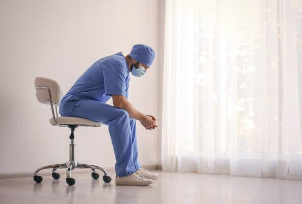 Physician sits near window demonstrating emergency medicine burnout