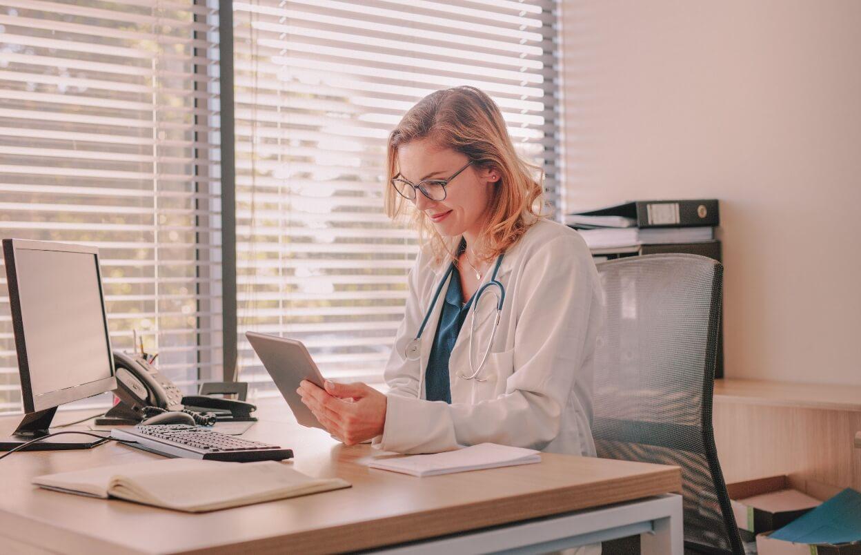 Female doctor using a digital tablet to access a healthcare marketing platform for her medical practice.