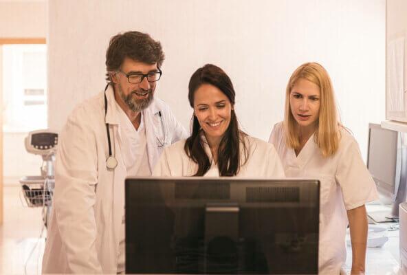 This is an image of 3 people in a medical practice looking at a computer. This is meant to show happiness as a result of streamlining a practice’s workflow.