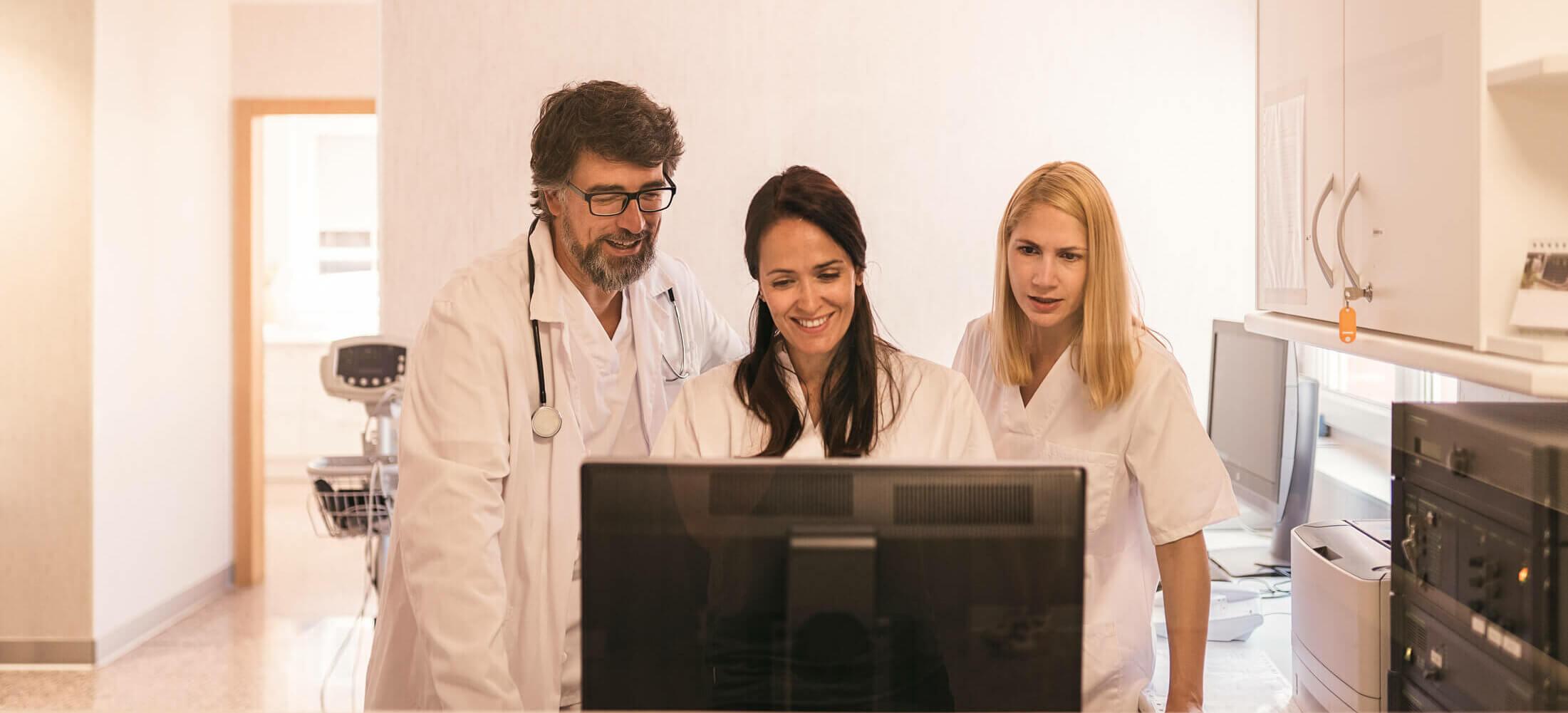 This is an image of 3 people in a medical practice looking at a computer. This is meant to show happiness as a result of streamlining a practice’s workflow.