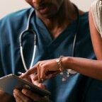 image of patient pointing to tablet screen next to doctor