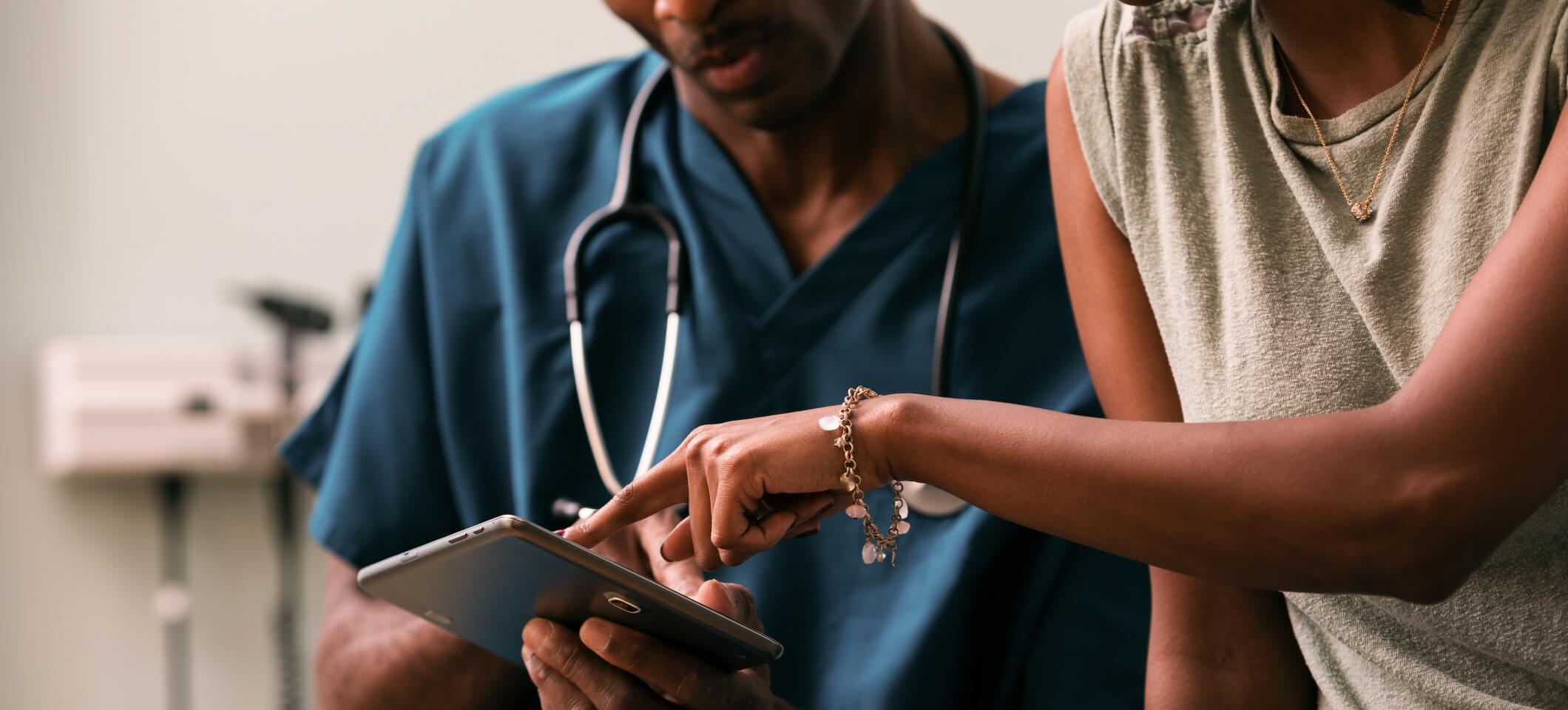 image of patient pointing to tablet screen next to doctor