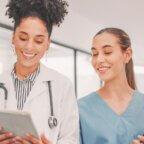 Female physician looking at digital tablet with medical practice staff member.