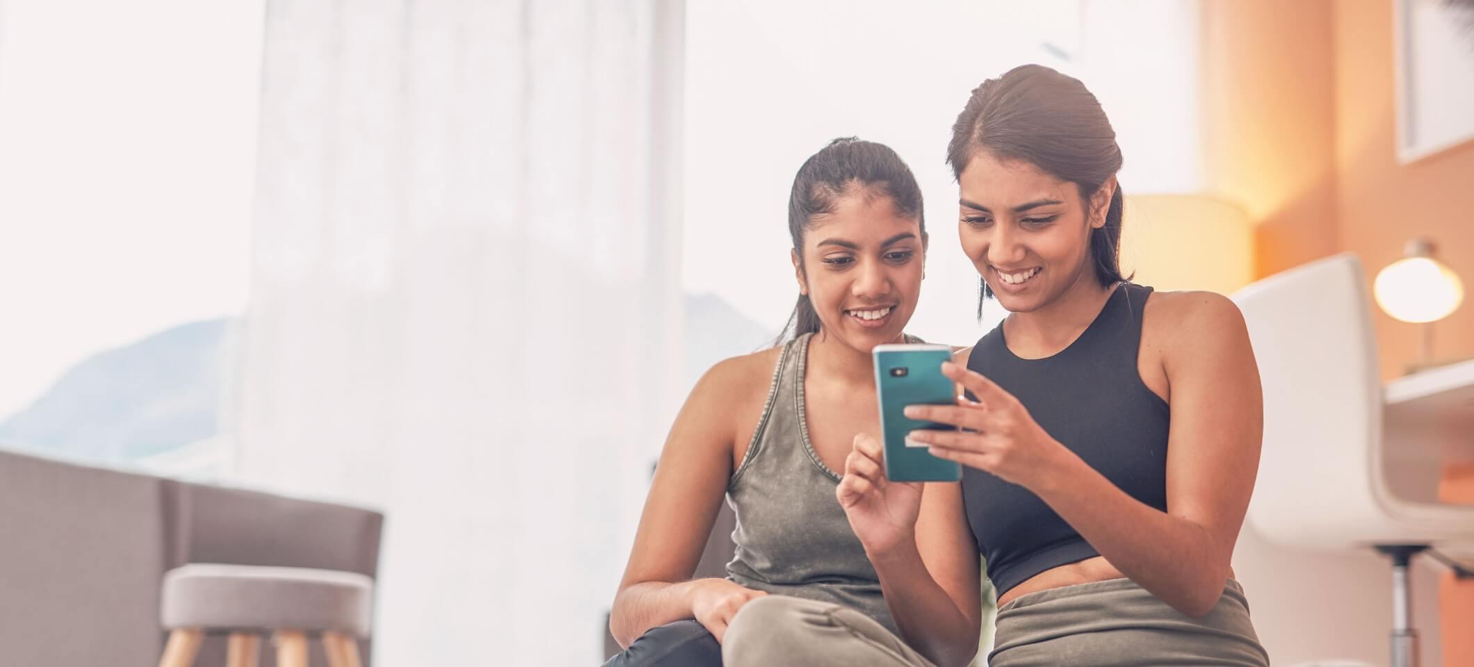 Two women looking at social media on a smartphone.