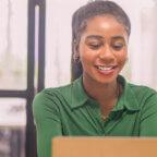 Smiling medical professional looks at laptop computer learning about blogging for healthcare marketing