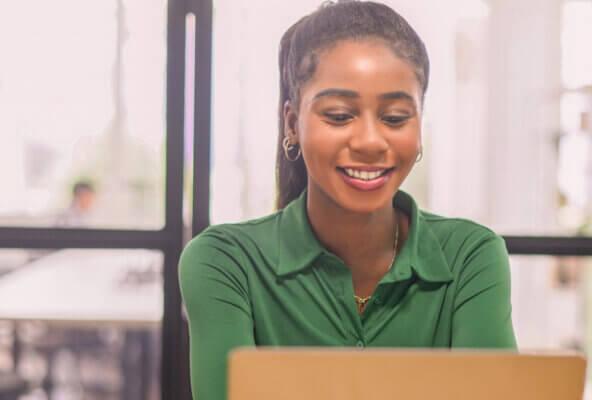 Smiling medical professional looks at laptop computer learning about blogging for healthcare marketing