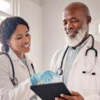 Two physicians look at the best medical pages on Facebook on a tablet