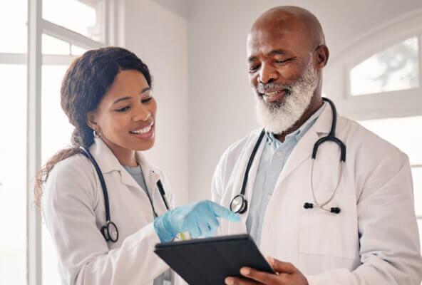 Two physicians look at the best medical pages on Facebook on a tablet