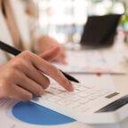 Medical practice manager makes financial plans with calculator after reading revenue cycle management news