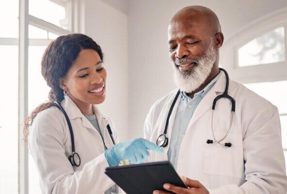 Physicians discuss their medical practice marketing budget while looking at tablet
