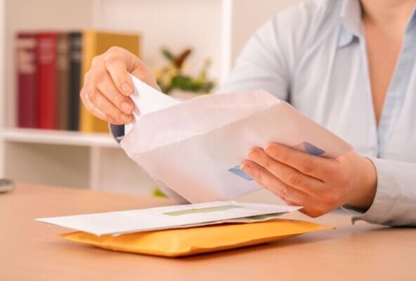 Person holding billing envelopes.