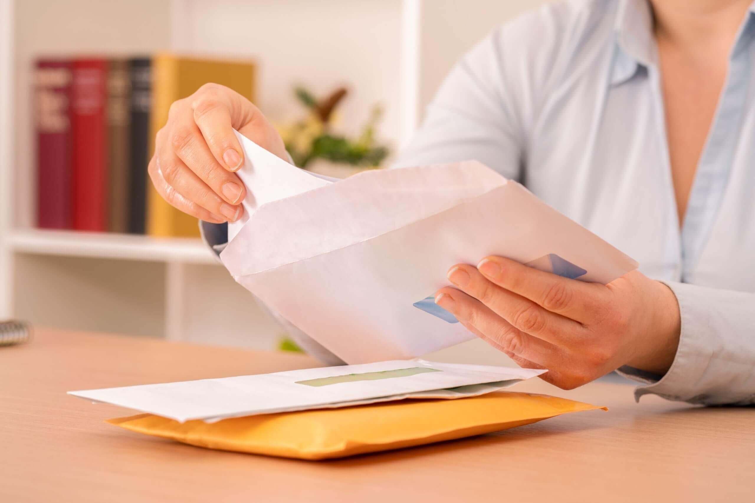 Person holding billing envelopes.