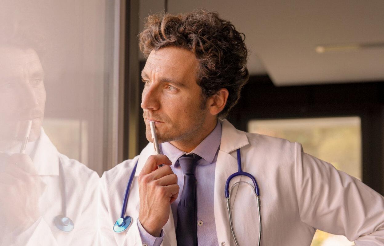 Doctor looks through window pondering solutions to physician burnout