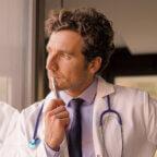 Doctor looks through window pondering solutions to physician burnout