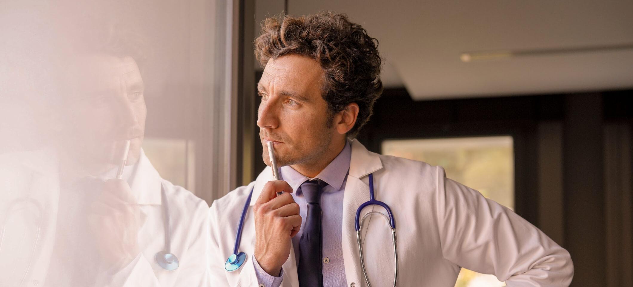 Doctor looks through window pondering solutions to physician burnout