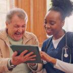 Staff member demonstrates how to improve customer service at your medical practice by helping patient with intake on tablet