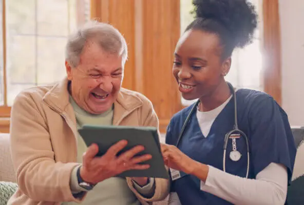 Staff member demonstrates how to improve customer service at your medical practice by helping patient with intake on tablet