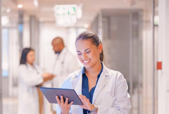 Physician smiles while reading about the least stressful medical specialties on tablet