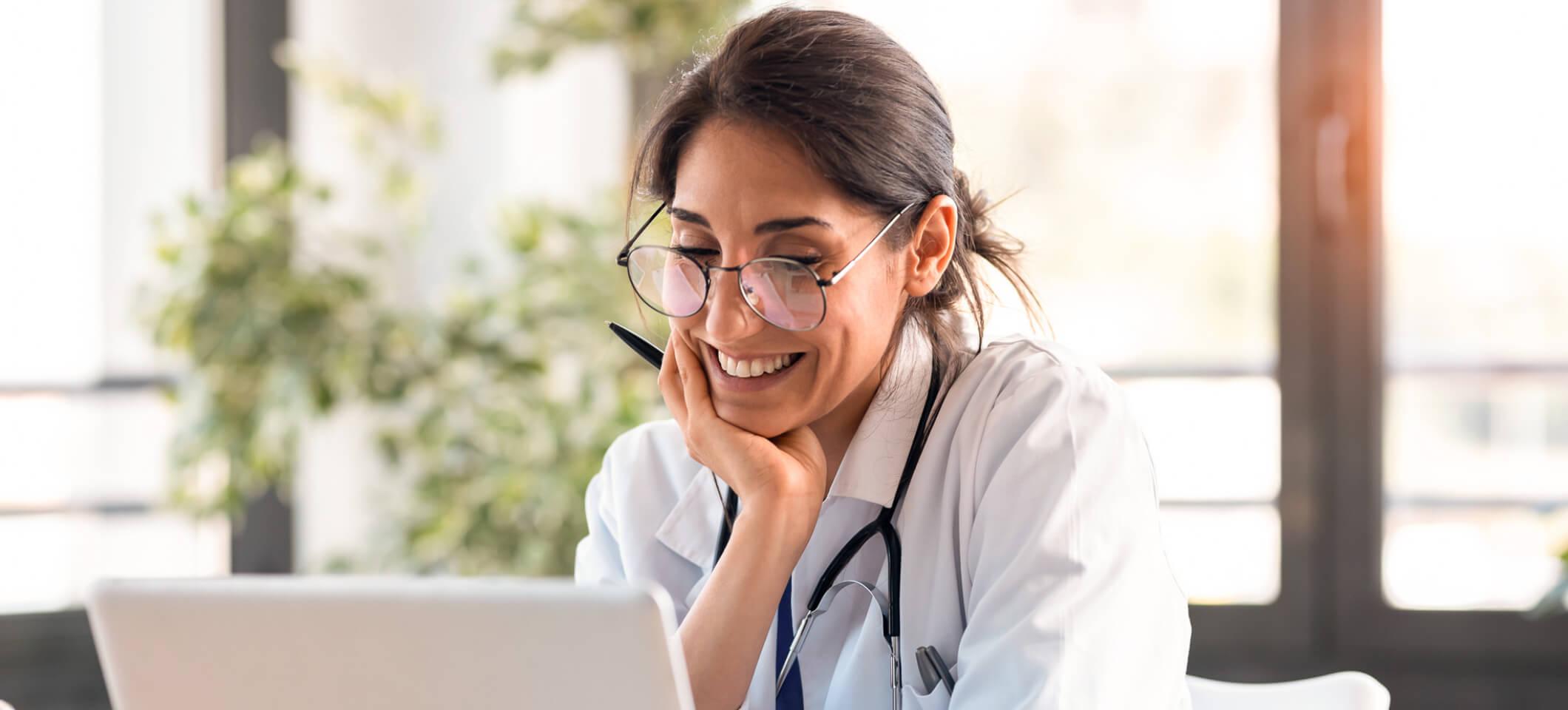 Physician reads April 2025 revenue cycle management healthcare news on laptop