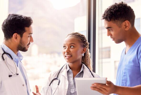 Physicians and clinical staff member look at tablet and collaborate on how to make prescribing easier