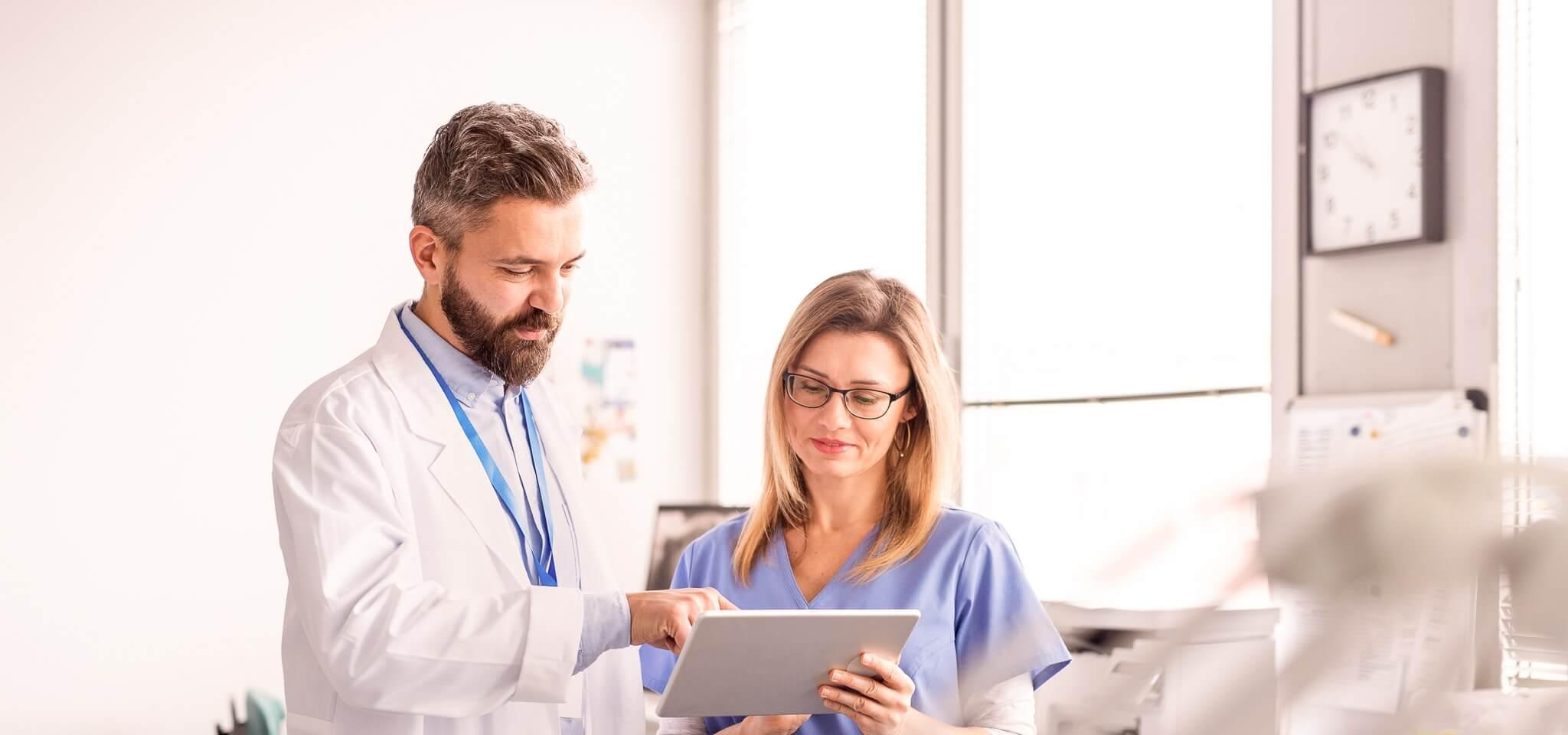 Healthcare professionals smile while reading about the best AI medical scribes on tablet