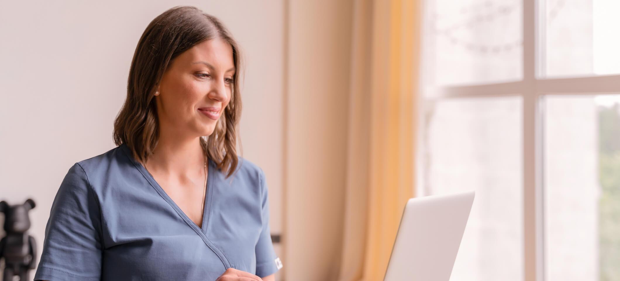 Physician reads on laptop about how AI eases cognitive load for doctors