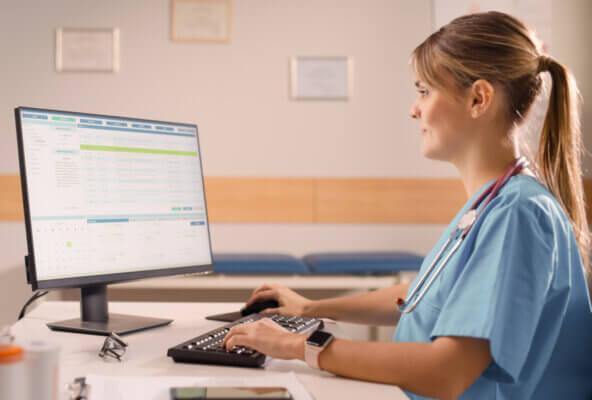 Physician looks at billing software on computer after reading August 2025 RCM healthcare news
