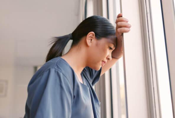 Physician looks out window demonstrating emotional fatigue in medicine