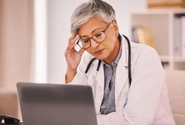Doctor sits at computer displaying primary care physician burnout